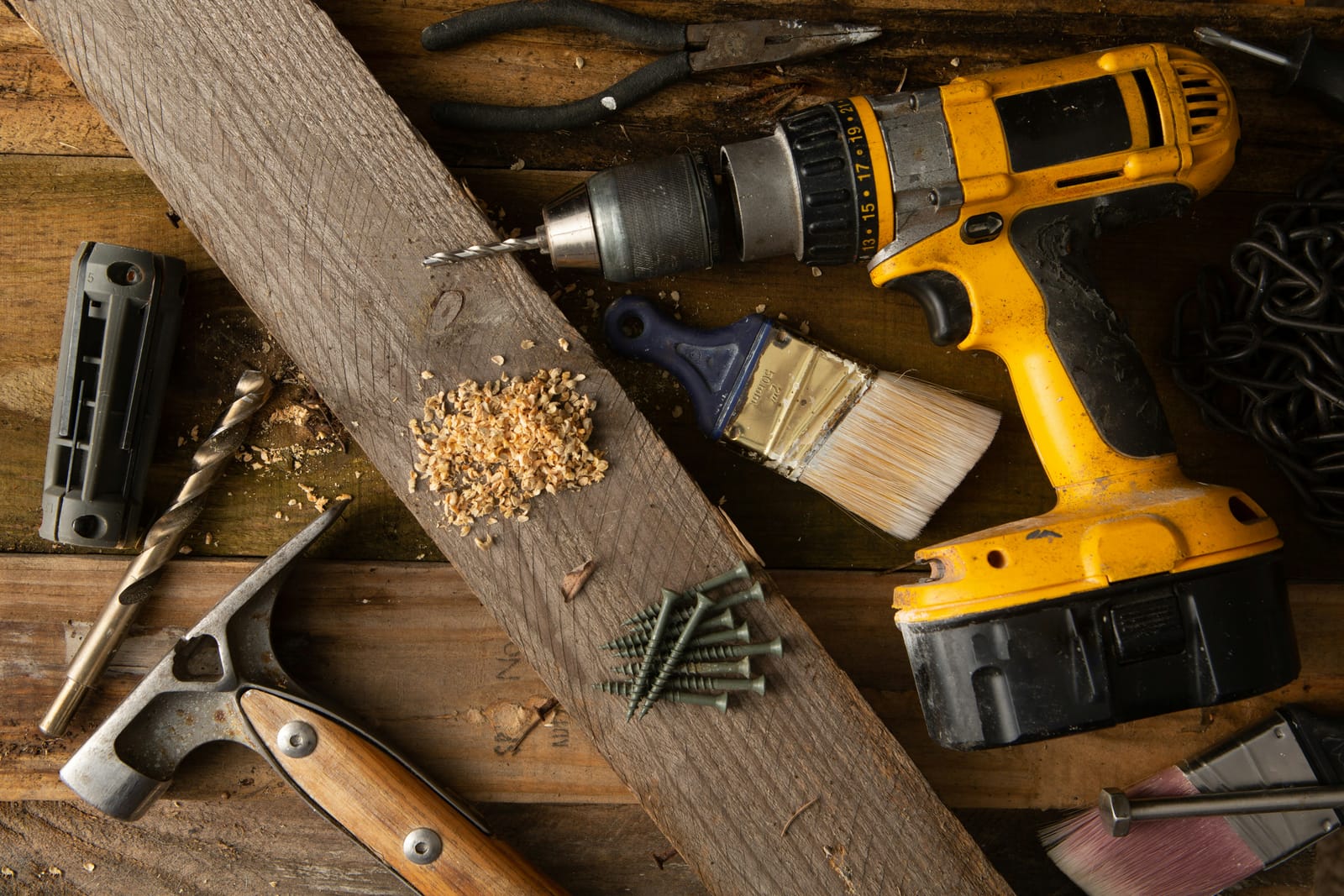 Drill, hammer, paintbrush and fasteners laid out on a workbench, ready for home repairs in the Heights